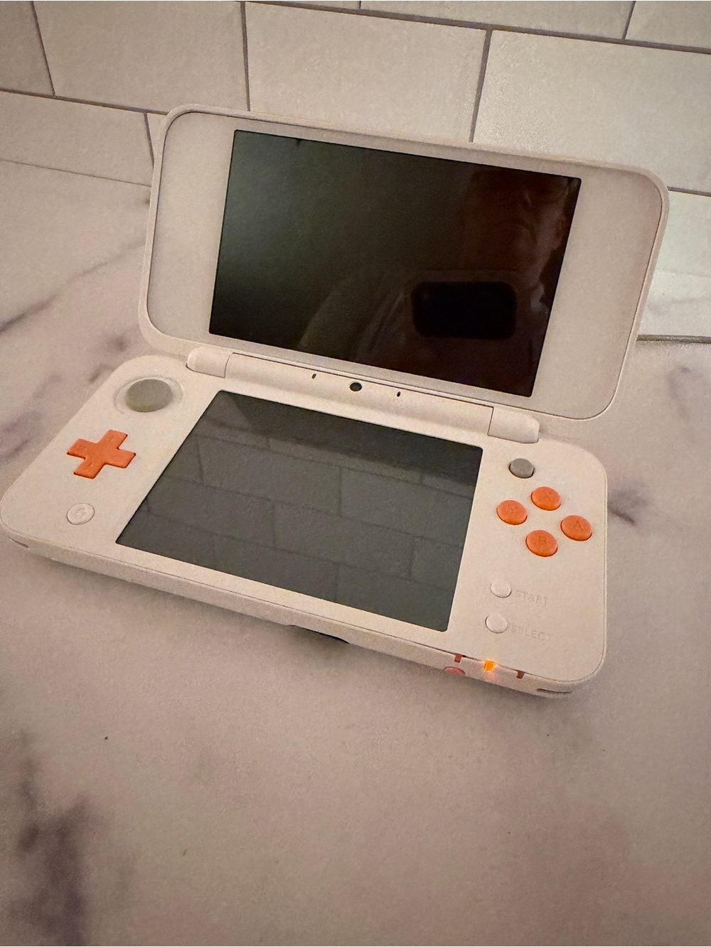 New Nintendo 2DS XL handheld console in the White/Orange colorway, model JAN-001